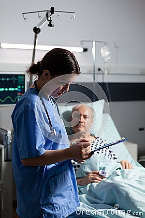 Medical nurse in scrubs taking notest on cliboard Stock Photo