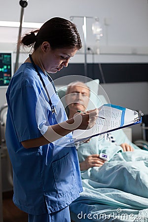 Medical nurse in scrubs taking notest on cliboard Stock Photo