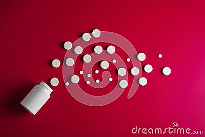 Medical pills round shape and bright bottle red background Stock Photo