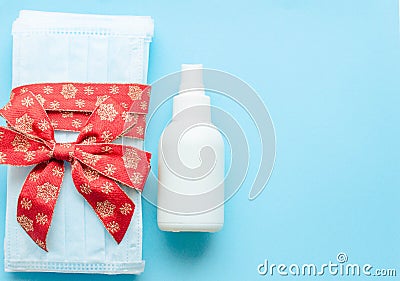 medical protective face masks as a gift with a red ribbon on a green background. Christmas and New Year 2021 decor painted firs an Stock Photo