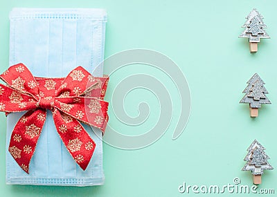 Medical protective face masks as a gift with a red ribbon on a green background. Christmas and New Year 2021 decor painted firs an Stock Photo