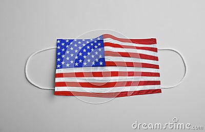 Medical protective mask with USA flag pattern on grey background, top view. Dangerous virus Stock Photo
