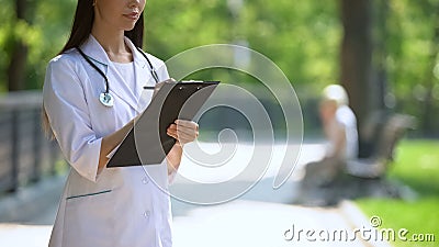 Medical researcher filling data in hospital park, woman smoking on background Stock Photo