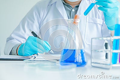 Medical science or male Compiling an Analysis Report in laboratory room research performs tests with blue liquid on test tube, Stock Photo