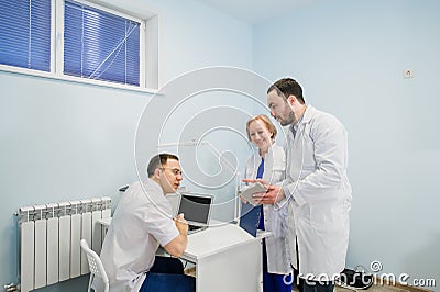 Medical staff discussing over medical reports using laptop and tablet pc. Healthcare professionals having discussion in Stock Photo