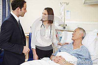 Medical Staff On Rounds Examining Senior Male Patient Stock Photo