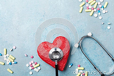 Medical stethoscope, red heart and drug pills on blue background top view. Healthy and blood pressure concept. Stock Photo
