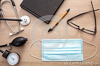 Medical stethoscope sphygmomanometer and protective mask on wooden background Stock Photo