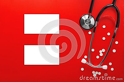 Medical stethoscope with two business cards and pills on clean red background. Layout for the designer Stock Photo