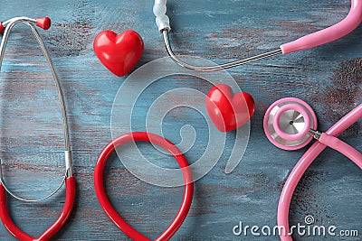 Medical stethoscopes and red hearts on wooden background. Cardiology concept Stock Photo