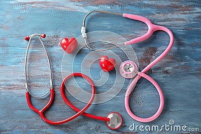 Medical stethoscopes and red hearts on wooden background. Cardiology concept Stock Photo
