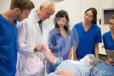 Medical students and professor checking pulse of student Stock Photo