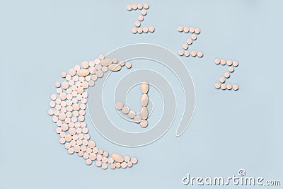 Medical supplement in the evening. Concept Insomnia, sleep problems. Pills in shape of the moon and alarm clock Stock Photo