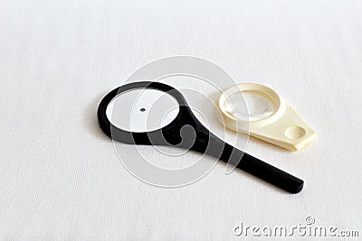 Rare ophthalmologic mirror in a dark plastic frame and a lens for examining the fundus on white gauze. Retro. Black and white phot Stock Photo