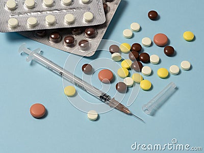 Medical supplies and a syringe are laid out on a blue background. A variety of drugs, pills Stock Photo