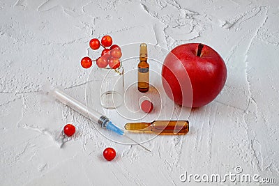 Medical syringe, ampules, red apple and berry Stock Photo