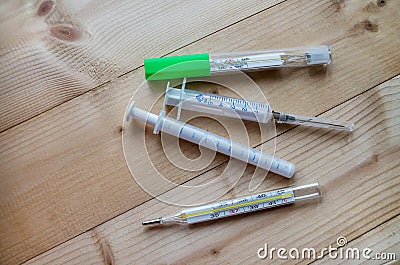 Medical syringe, thermometers on a wooden table Stock Photo