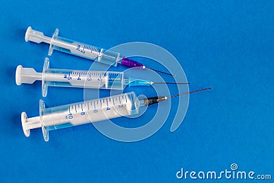 Medical syringes of different capacities lie on a blue surface Stock Photo