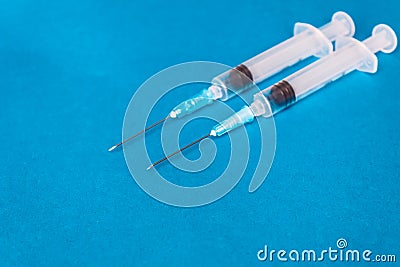 Medical syringes of different capacities lie on a blue surface Stock Photo