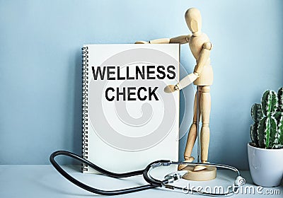 Medical table with a wooden person along with a stethoscope. Inscription WELLNESS CHECK on the clipboard with the holder. Health Stock Photo
