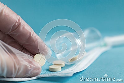 Medical tablets close on the blue background.paramedic hand holds pill. Coronavirus, flu respiratory disease concept Stock Photo