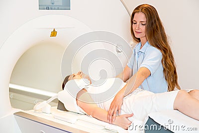 Medical technical assistant preparing scan of shoulder with MRI Stock Photo
