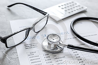 Medical treatmant billing statement with stethoscope and glasses on stone background Stock Photo