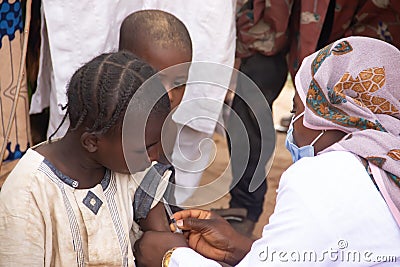 Medical worker doing routine immunization vaccination for children under 9 years, in refugee camp in Africa Editorial Stock Photo