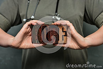 A medical worker with a stethoscope holds the word `hope` made of wooden typographic letters Stock Photo