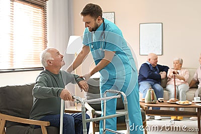 Medical worker taking care of man with walker in geriatric hospice Stock Photo