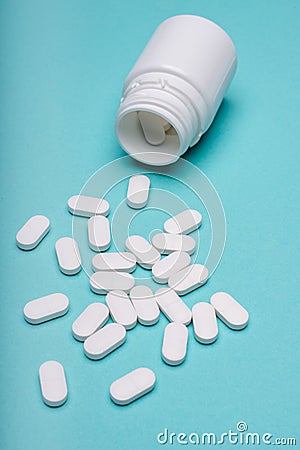 Medication bottle and white pills spilled on blue pastel coloured background. Medication and prescription pills. Stock Photo