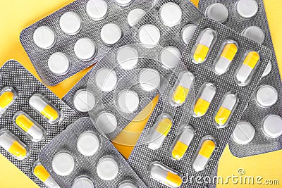 Medication concept. Various drugs in shiny blisters on a yellow background. Prescripted pills. Healthful medical treatment. Stock Photo