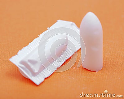 Medication in disposable plastic suppository moulds on orange. Rectal drug administration Stock Photo