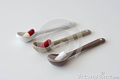 medication pills inside ceramic spoons. drugs, antibiotics, analgesics, narcotics Stock Photo