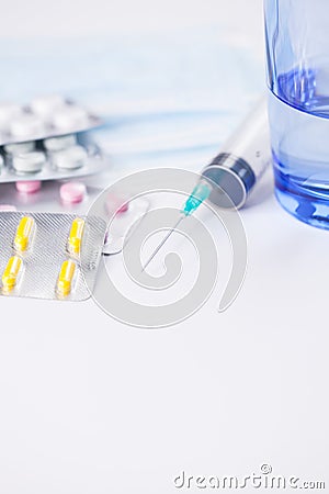 Medications pills drug, glass of water, mask and syringe. Flu outbreak and coronavirus or influenza. Stock Photo