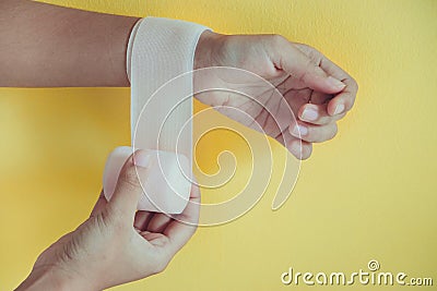 Medicine bandage on injury female wrist on yellow background Stock Photo