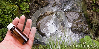 Medicine bottle on the water source background. A glass bottle with herbal extract in your hand Stock Photo