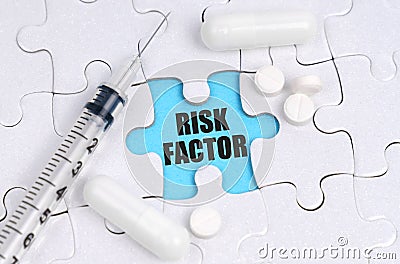 There are pills and a syringe on the white puzzles. Inside on a blue background the inscription - RISK FACTOR Stock Photo