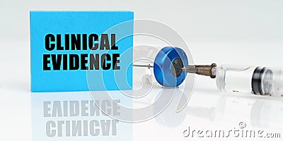 On a white reflective surface are a syringe, an injection and a blue plaque that says - Clinical Evidence Stock Photo