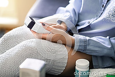 Medicine for flu, virus or pain. Ill woman reading label information of a medical product. Medication for cough and recovery. Stock Photo