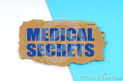On a blue and white background lies a piece of cardboard with the inscription - Medical Secrets Stock Photo