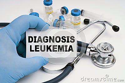 There is a stethoscope on the table, the doctor is holding a business card with the inscription - diagnosis LEUKEMIA Stock Photo