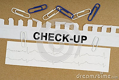On the table lies a cardiogram, paper clips and paper with the inscription - CHECK-UP Stock Photo