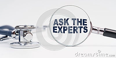 There is a stethoscope on the table, a magnifying glass with the inscription - ASK THE EXPERTS Stock Photo