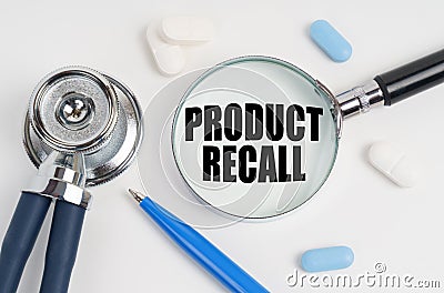 On a white surface lie pills, a pen, a stethoscope and a magnifying glass with the inscription - PRODUCT RECALL Stock Photo