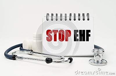 On a white table lies a stethoscope, pills and a notebook with the inscription - Stop EHF Stock Photo