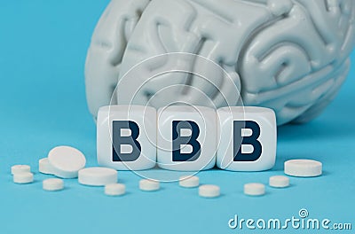 Cubes lie on the table among the pills and imitation of the brain. The text on the dice - BBB Stock Photo