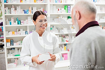 Happy female pharmacist giving medications to senior male customer Stock Photo