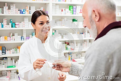 Beautiful young pharmacist selling medications to senior patient Stock Photo