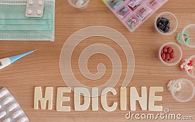 Medicine word in wood with capsule and pills, thermometer, mask and pillbox in wood background close up Stock Photo